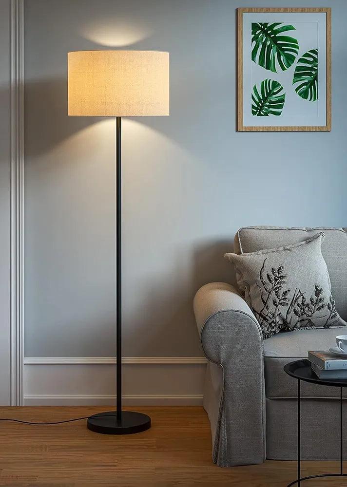 Elegant black floor lamp placed in a modern living room, lights off – minimalist design and round base