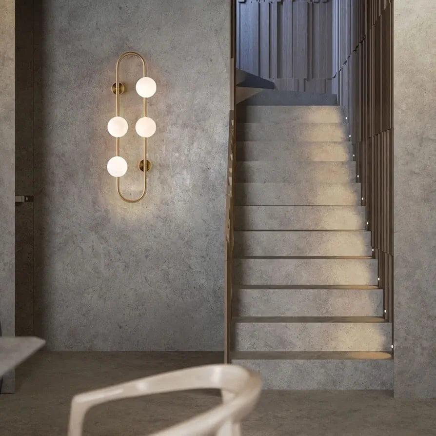 Modern gold wall lamp light with three frosted globes illuminating a stylish staircase