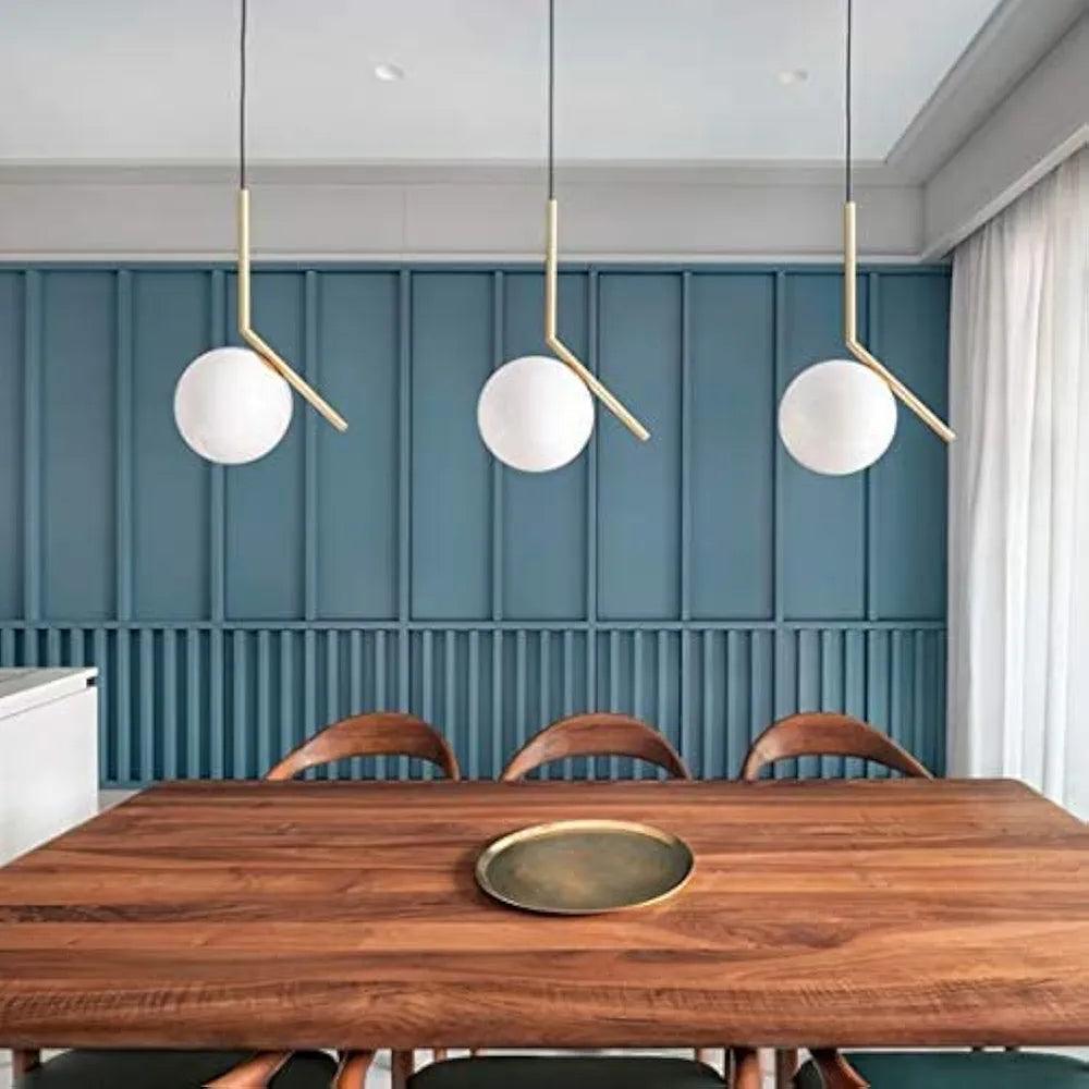Modern N I CREATIONS hanging lamp trio over a wooden dining table with a stylish blue wall backdrop