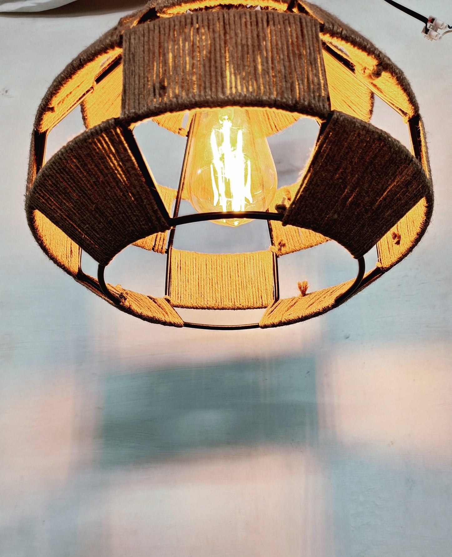 Warm-lit jute rope hanging lamp showing interior glow and texture