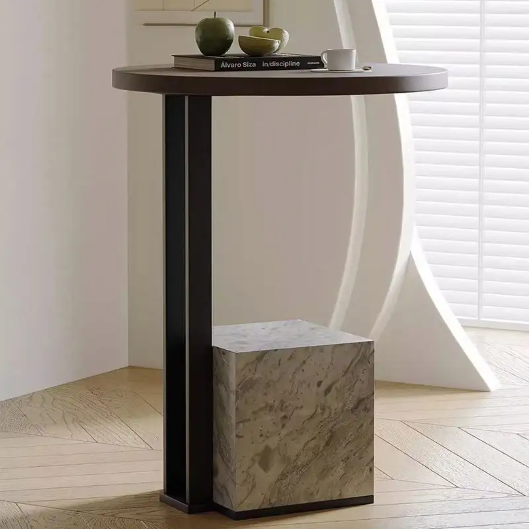 Small round table with a marble base in a room with a window and light-colored floor.