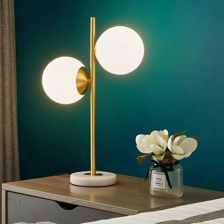 Elegant N I CREATIONS table lamp desk with dual globe lights and a gold stand on a bedside table