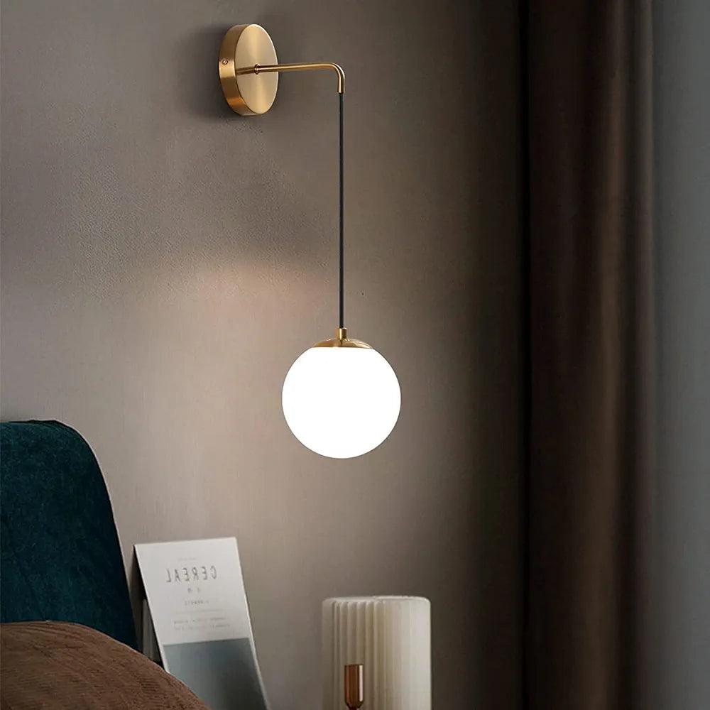 Modern wall lamp with a golden arm and round frosted glass shade, perfect for home decor