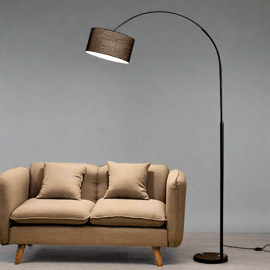 Modern black arch floor lamp switched on beside a sofa — ideal for cozy living rooms.