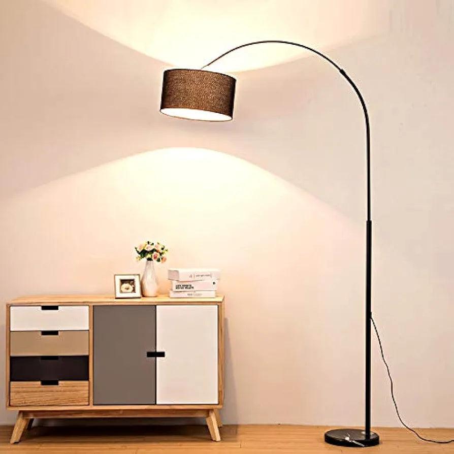 Black arch floor lamp with light on — adds ambiance to living space.