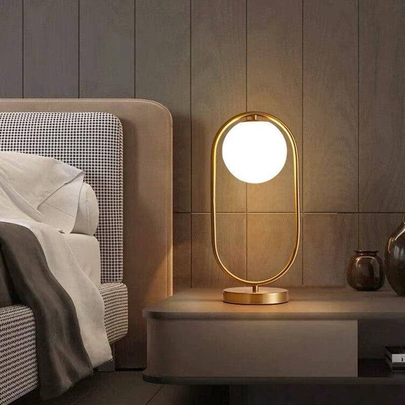 Elegant night table lamp with a gold frame and round glass shade for modern bedroom decor