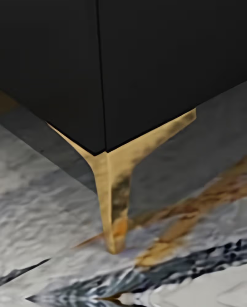 Close-up of a black cabinet with a gold leg on a marble floor.