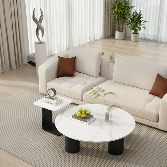 Round white marble coffee table with black legs in front of a beige sofa.